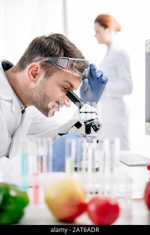 selective focus of smiling molecular nutritionist using microscope in lab Stock Photo