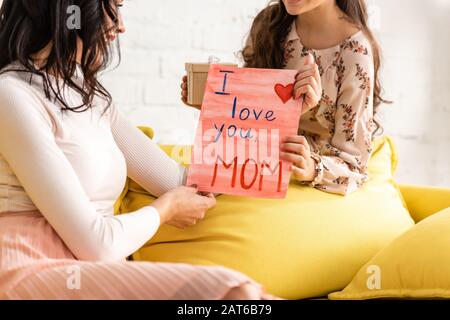cropped view of child presenting mothers day card with i love you mom inscription to mother Stock Photo