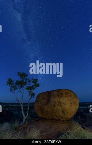 Light painting the devil's marble and a desert gum with milky way core in the background. Stock Photo