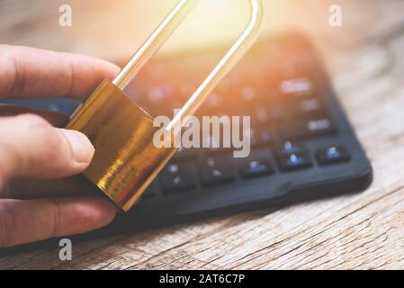 Padlock in hand data security systems computer with locked padlock on keyboard for protect crime by an anonymous hacker internet and data network / te Stock Photo