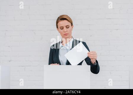 attractive businesswoman voting near brick wall Stock Photo