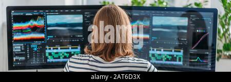 panoramic shot of editor working near computer monitors Stock Photo