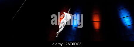 panoramic shot of acrobat performing on pole in arena of circus Stock Photo
