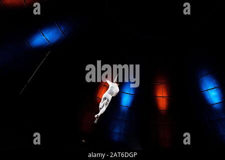 back view of acrobat performing on pole in arena of circus Stock Photo