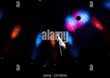 low angle view of acrobat performing upside down on pole in arena of circus Stock Photo
