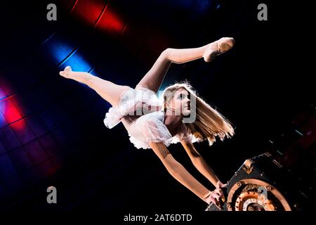 flexible girl doing handstand while performing in arena of circus Stock Photo