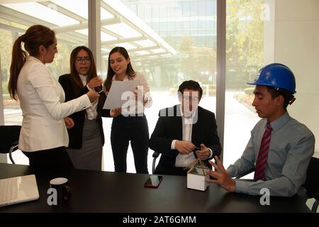 Architect explains to the future owner of the house using a conceptual mock-up of the benefits, while the wife analyzes the contract to be signed with Stock Photo