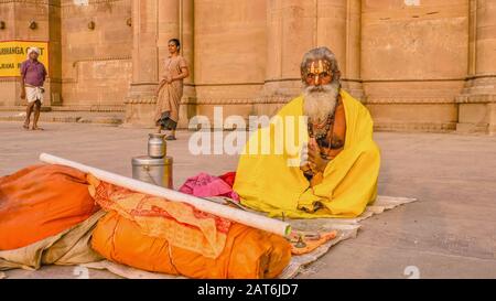 Varanasi, India - Nov 12, 2015. A Hindu sadhu sits with his few worldly possessions on a mat on Darbhanga Ghat. Stock Photo