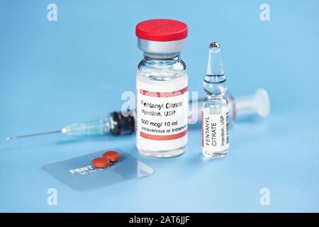 Fentanyl citrate injection ampule, vial, clear fentanyl dermal patch, tablets and syringe on blue tray. Stock Photo
