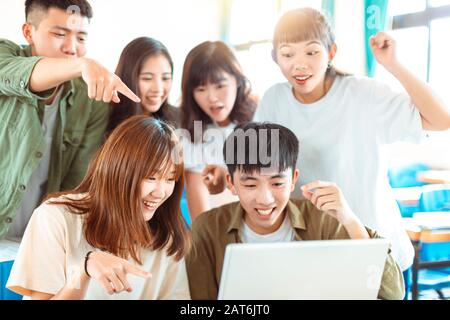 excited college students looking at laptop  in classroom Stock Photo