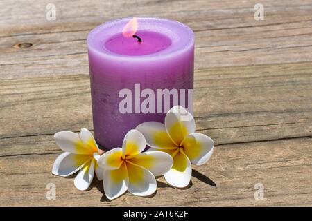 Burning candle on timber deck. Stock Photo