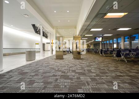 Almost empty airport Terminal early in the morning with very few passengers waiting. Stock Photo