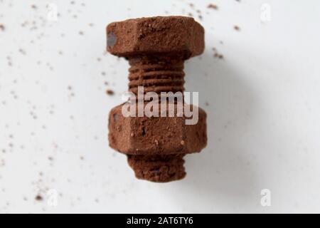 Rusty bolt and nut made of chocolate isolated on white background. Chocolate chip scattered on smooth surface. Mechanic gearing background. Father's d Stock Photo