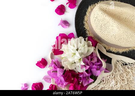 Pink flowers in string bag with hat on white background. Flat lay, top view. Womans day and Mothers day concept. Stock Photo