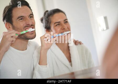 Fun attractive couple brushing teeth together Stock Photo