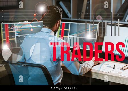 back view of man working near computer with graphs and traders letters Stock Photo