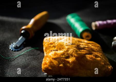 Composition with yellow pincushion and threads on black background. Sewing accessories. Stock Photo
