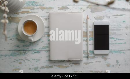 Top view of rustic workplace with smartphone, stationery and coffee cup on vintage table background Stock Photo