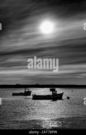 Boats in silhouette in Orford, Suffolk, UK Stock Photo
