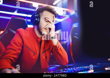 Streamer young man professional video gamer regrets loser playing online games computer, neon color Stock Photo