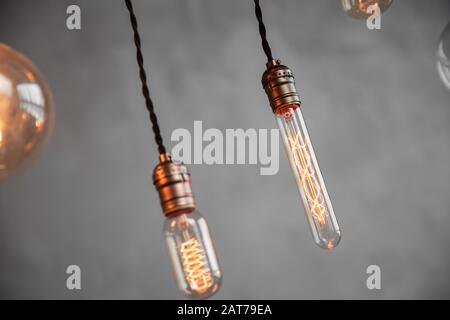Edison retro lamp incandescent bulbs on gray plaster wall background in loft. Concept Vintage style. Copy space Stock Photo