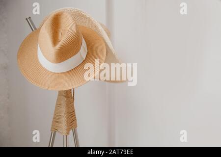 Straw yellow hat hanging on a white wooden coat hanger, scandinavian style minimalism. Travel concept Stock Photo