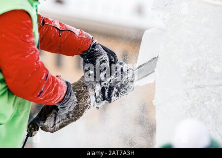 Ice sculpture carving man use chainsaw cut frozen winter Stock Photo