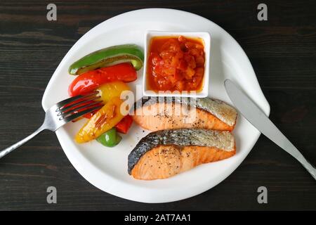 Pan Fried Salmon Steaks with Grilled Colorful Bell-peppers and Provencal Sauce on White Plate Stock Photo