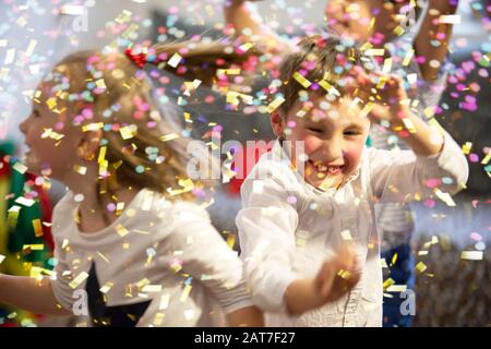 Background party for children. Multicolored confetti on the background of joyful faces. Stock Photo