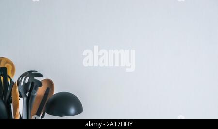 Black and brown kitchen utensils in left hand corner against white wall background. Minimalist and urban living concept with wooden and plastic tools Stock Photo