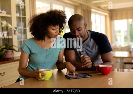 Happy young couple using tablet computer in the kitchen Stock Photo