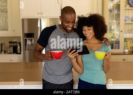 Happy young couple using tablet computer in the kitchen Stock Photo