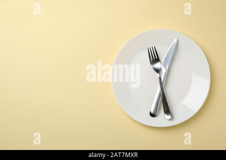 Plate with fork and knife on beige background, top view Stock Photo