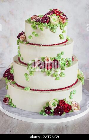 Festive four-level white elegant cake with cream flowers, wedding cake, cream flowers in the Malaysian technique Stock Photo