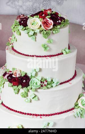 Festive four-level white elegant cake with cream flowers, wedding cake, cream flowers in the Malaysian technique Stock Photo