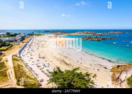 Aerial view over the beach of Greve Blanche in Tregastel, Brittany, on a sunny summer day with people sunbathing and enjoying the turquoise sea. Stock Photo