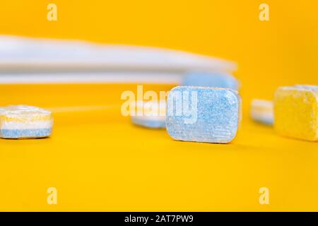 Cleaning dishwasher tablets on a yellow background. Group of bright colored soap tablet for washing dishes. Cleaning equipment detergent pods for kitc Stock Photo