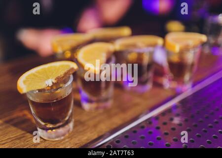 Dried candied orange, lime and lemon wheels in large glass container with contents also arranged on butcher block around jar with raw sugar and metal Stock Photo