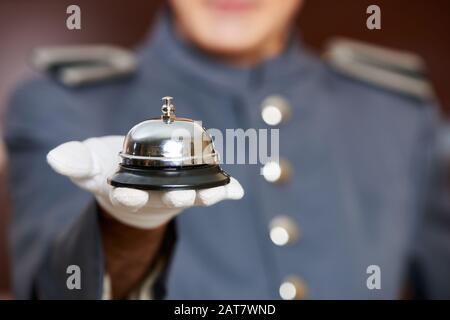 Hotel bell on hand by a concierge at the hotel Stock Photo