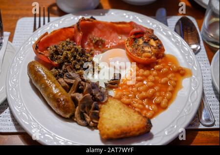 White board with full Scottish breakfast with bacon, fried egg, beans, tomato, roasted sausage, pudding, hash browns and haggis Stock Photo