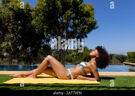 Young woman relaxing near swimming pool on a sunny day Stock Photo