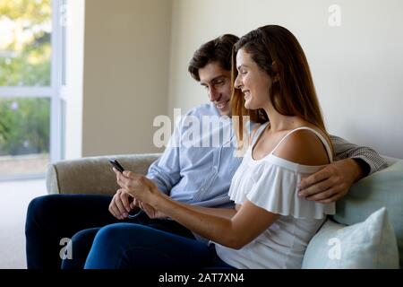 Happy young couple using mobile phone on sofa Stock Photo