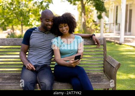 Happy young couple sitting on a bench in the garden Stock Photo