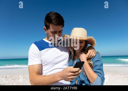 Young couple looking at smartphone at the beach Stock Photo