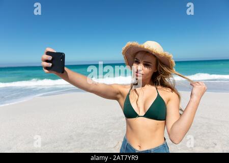 Beach selfies. a young woman taking a selfie while lying on the beach
