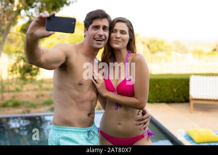 Happy young couple taking selfie near swimming pool Stock Photo