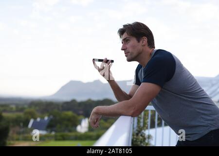 Young man talking on his mobile phone on terrace Stock Photo