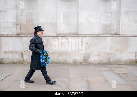 London, UK. 31 January 2020. A man dressed as an undertaking slowly walks along Whitehall holding a European Union funeral reef with 11 yellow stars. Stock Photo