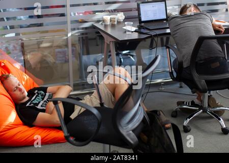 Belarus, Minsk city, August 06, 2017. Programmers Office. Tired IT people sleep at work. Two men fell asleep at the workplace. Stock Photo