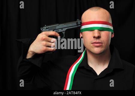 young blindfolded man in black shirt with gun to his head Stock Photo